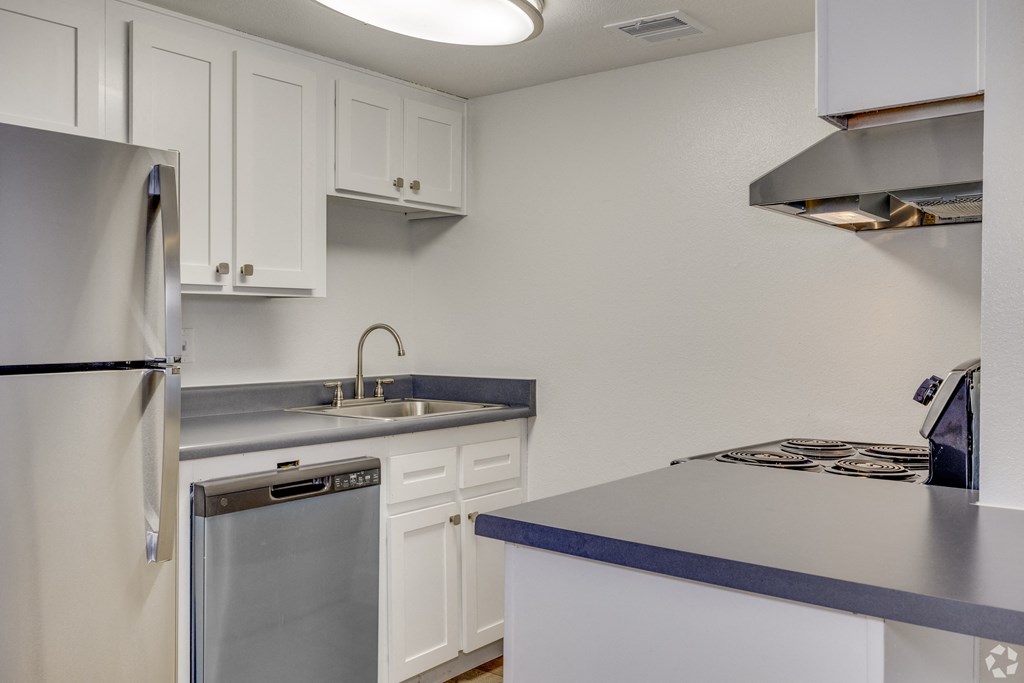 an empty kitchen with white cabinets and a stainless steel refrigerator