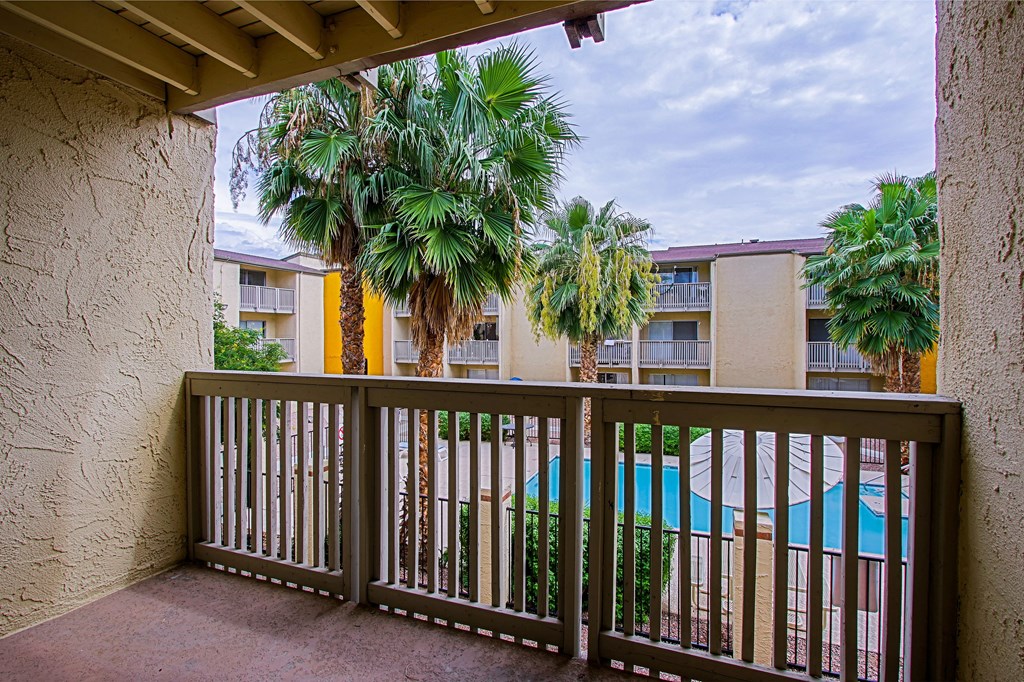 a balcony with a view of a pool and palm trees