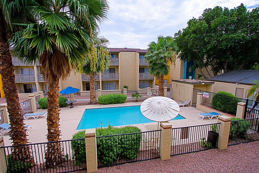 a swimming pool with a umbrella in front of an apartment building