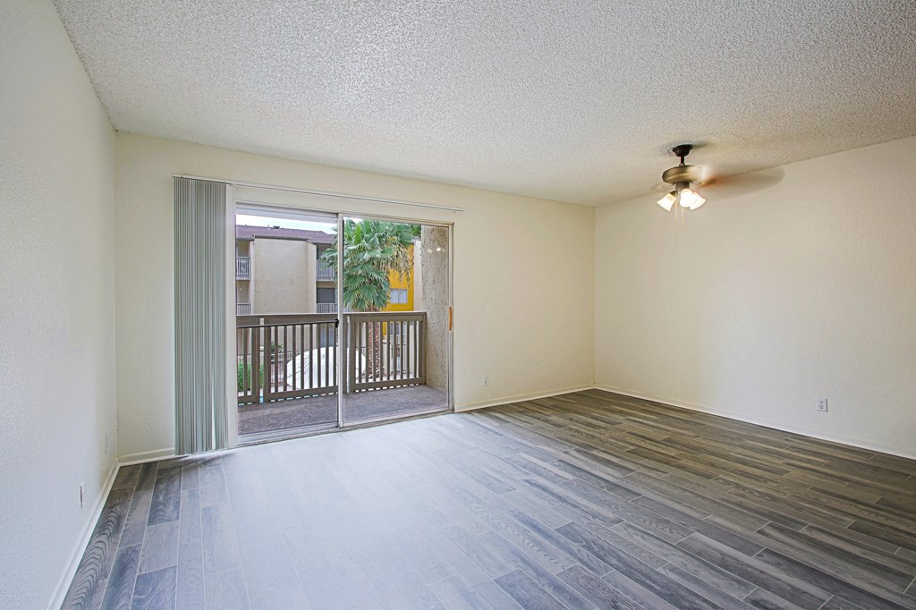 an empty living room with a sliding glass door to a balcony