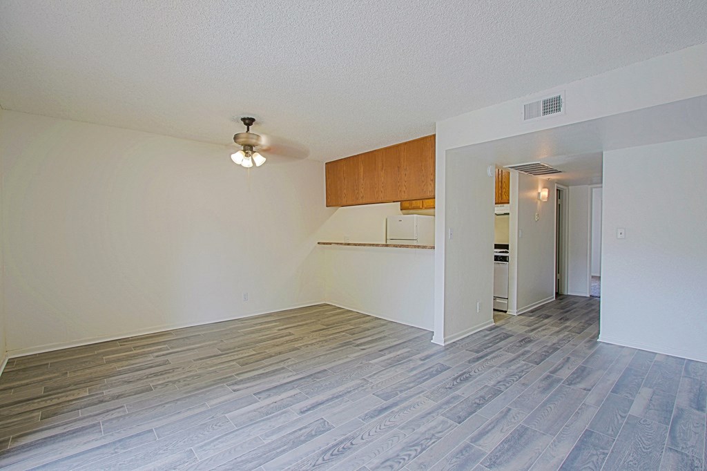 the spacious living room with wood flooring and a ceiling fan