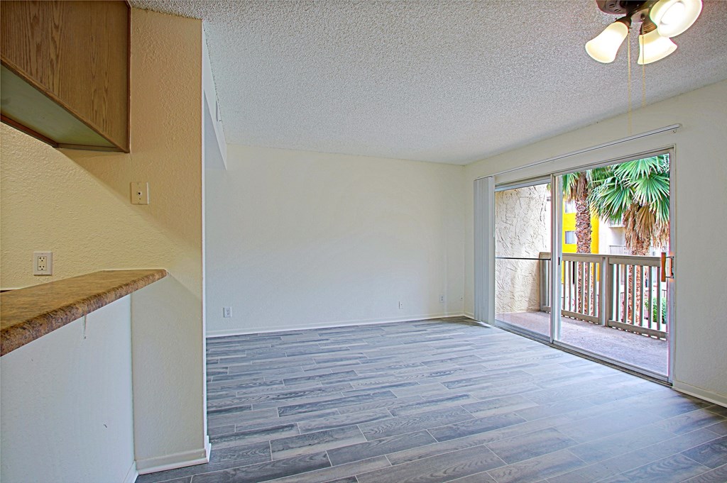 an empty living room with a sliding glass door to a balcony