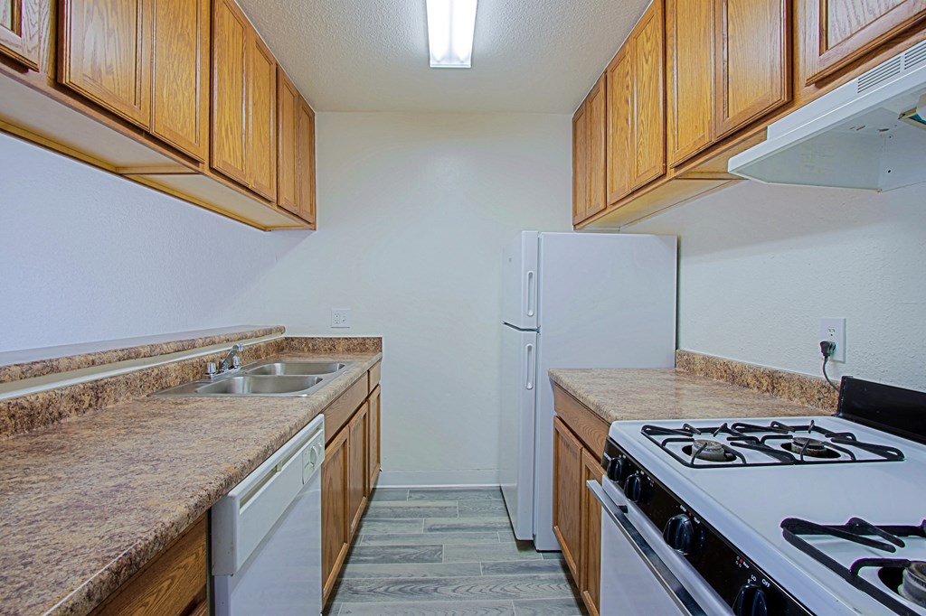 the kitchen of our apartments has a stove refrigerator and sink