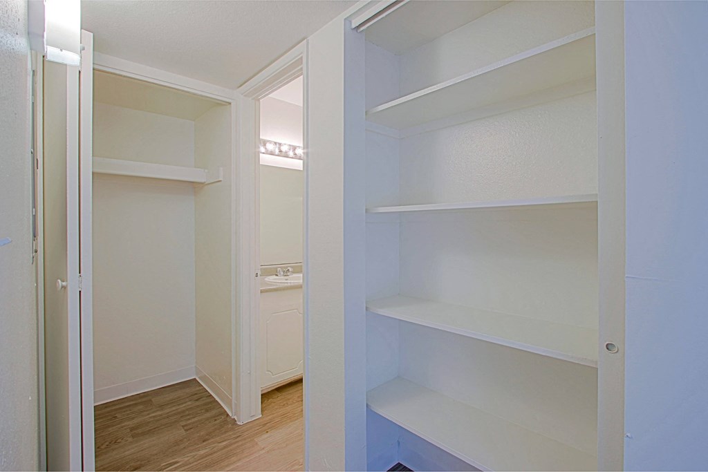 a walk in closet with white shelves and a laundry room