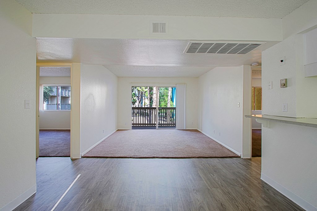 an empty living room with wood floors and a balcony