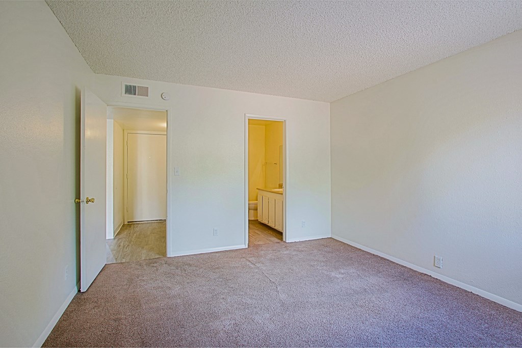 an empty room with carpet and a door to a bathroom