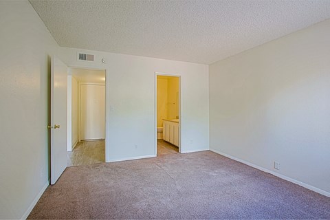 an empty room with carpet and a door to a bathroom