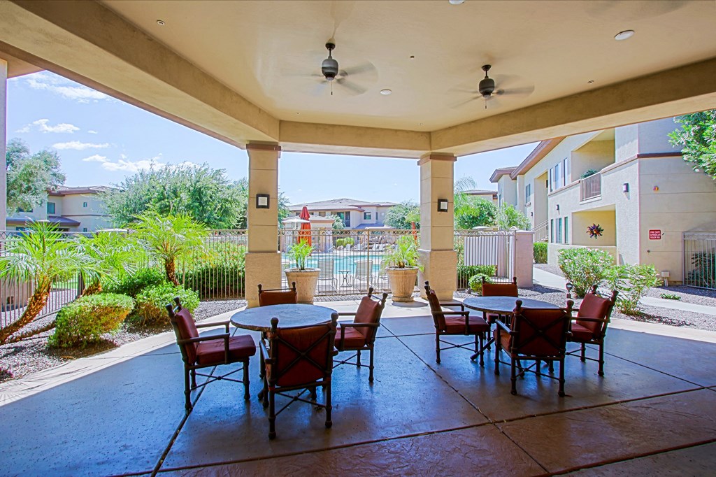 an outdoor patio with tables and chairs and a pool