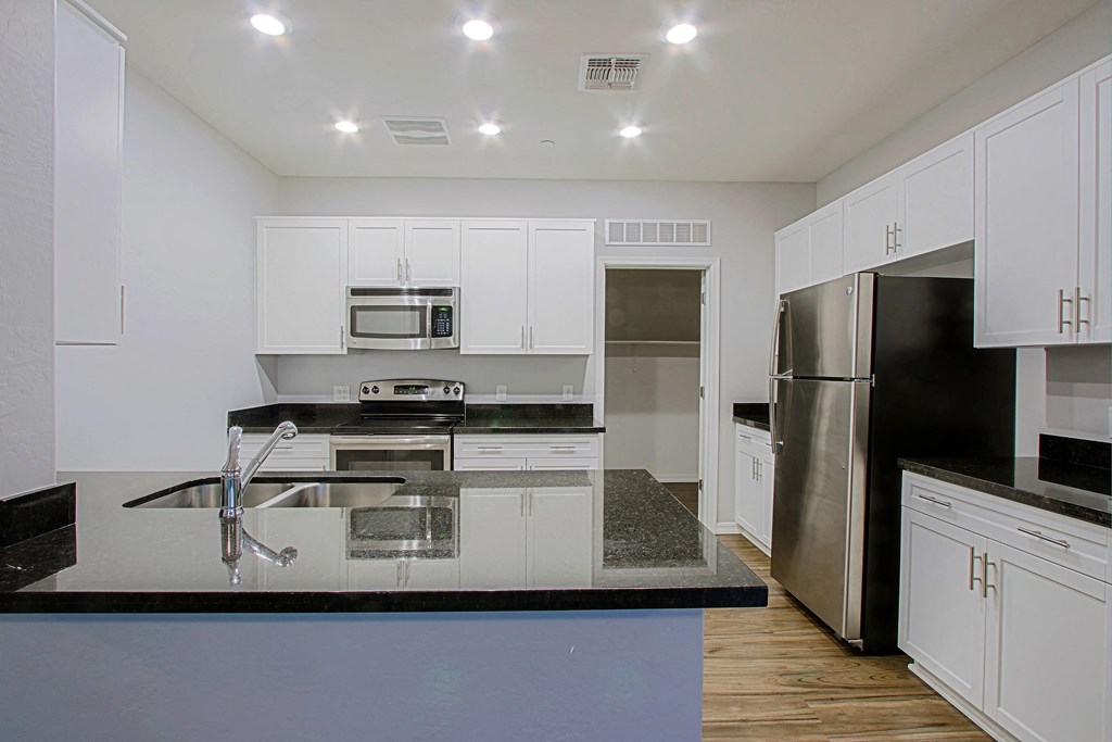 a kitchen with white cabinets and black counter tops