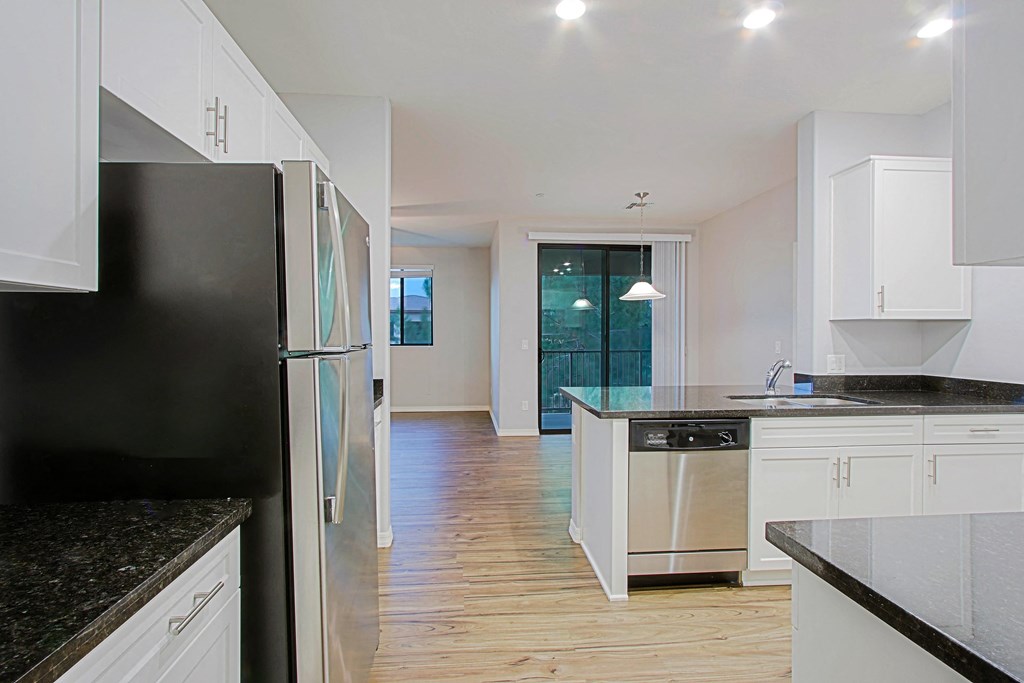 a kitchen with white cabinets and a black refrigerator