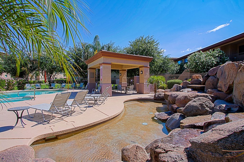 a resort style pool with a water feature and a pavilion