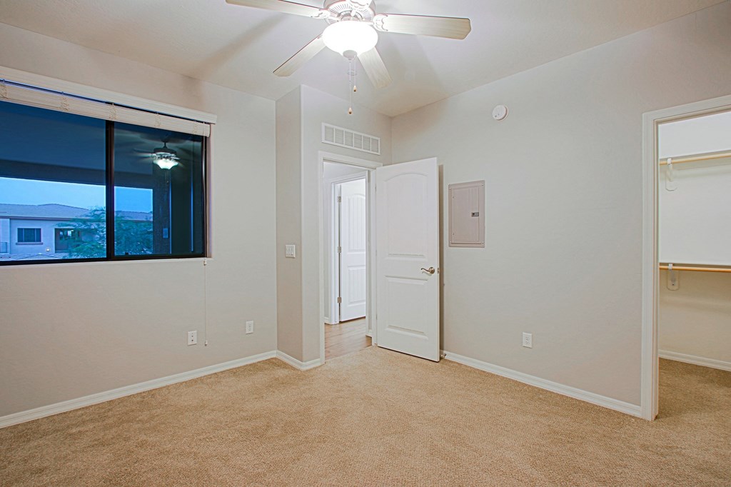 an empty living room with a ceiling fan and a window