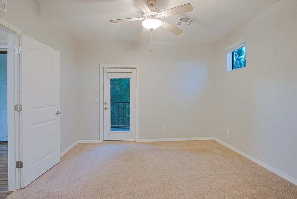 an empty room with a ceiling fan and a door to a closet