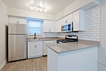 an empty kitchen with white cabinets and stainless steel appliances at Allora Phoenix in Phoenix, Arizona