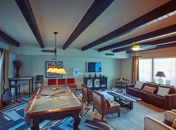 Game room with a pool table and couches with exposed beam ceilings at The Viridian in Scottsdale, 85250