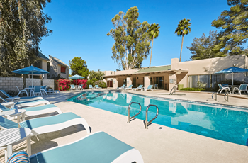 Large Pool with Blue Chaise Lounge Chairs Surrounding at The Viridian Apartments in Scottsdale, AZ
