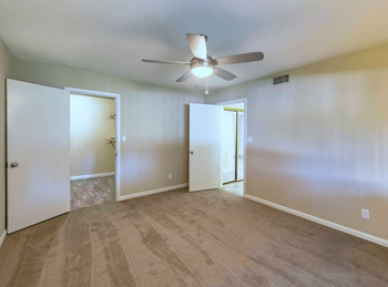 Spacious Bedroom with a ceiling fan and plsuh tan carpeting at The Viridian Apartments in Scottsdale, AZ
