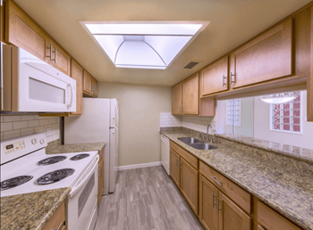 a kitchen with wooden cabinets and white appliances and granite counter tops at The Viridian Apartments in Scottsdale, Arizona 85250