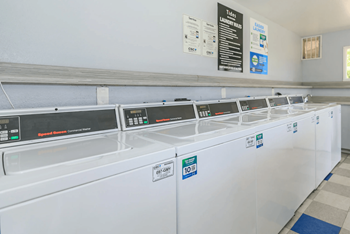 Laudry facilities with a row of washers at Tides on Southern in Mesa, Arizona