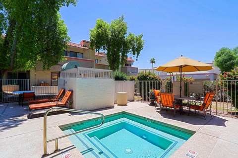 A pool with a slide and chairs around it.