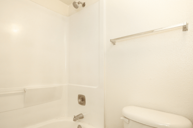 a white bathroom with a white toilet and a shower