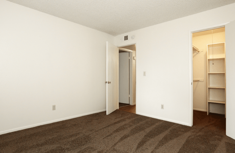 an empty bedroom with a closet and a door to the bathroom