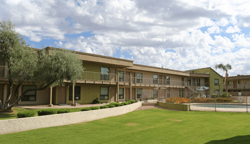 the view of an apartment building with a lawn and a fence
