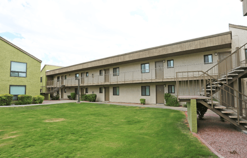 an exterior view of an apartment building with a yard and stairs