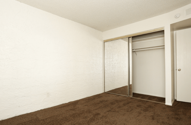 an empty room with a carpet and a closet