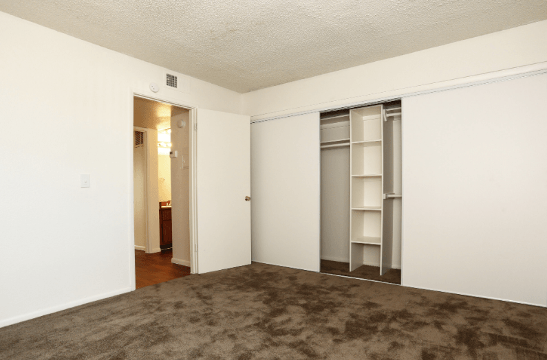 an empty living room with white walls and closet doors
