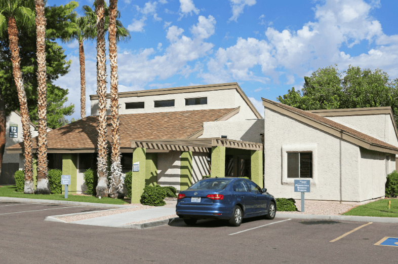 a blue car parked in front of a building with palm trees