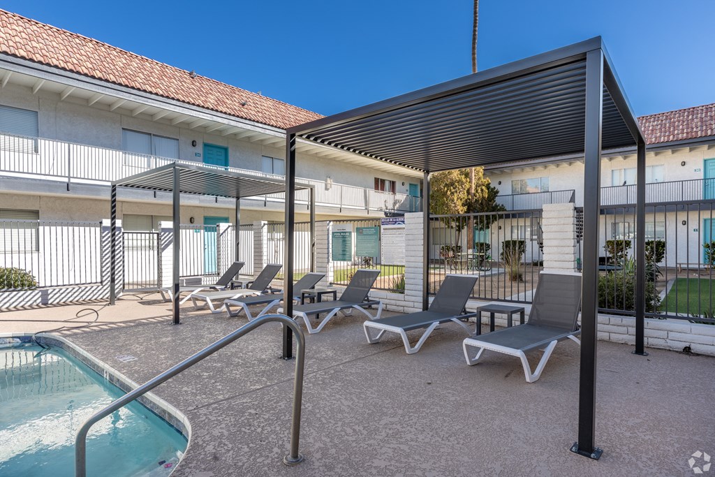 a patio with lounge chairs and a pool and a building