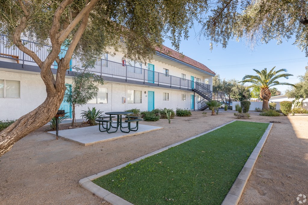 a courtyard with a green lawn and a building in the background