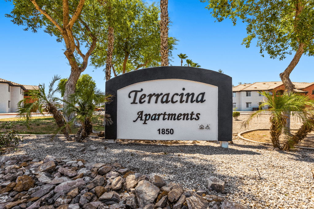 A sign for TerraCina Apartments is displayed in front of some trees.