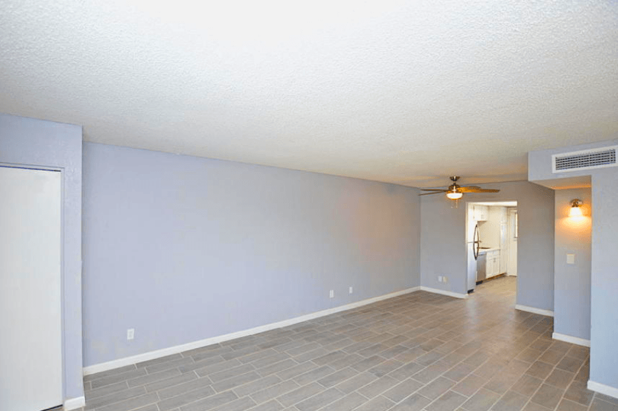 an empty living room with a ceiling fan