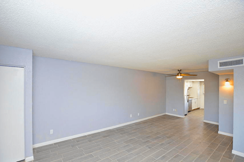 an empty living room with blue walls and a ceiling fan