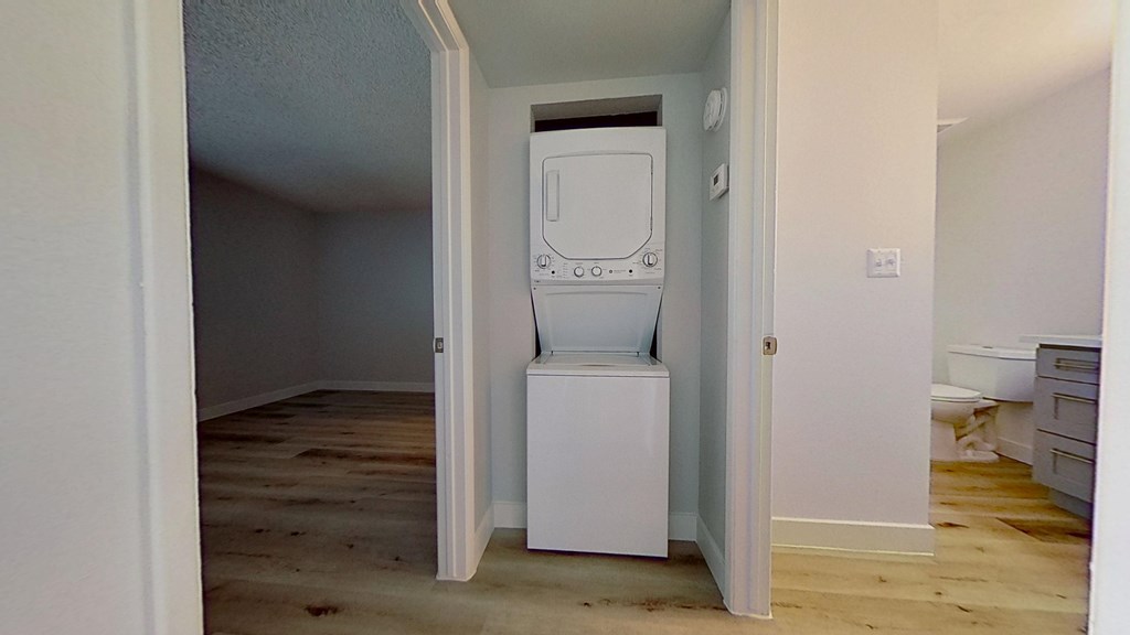 A white fridge in a room with wooden floors and white walls.
