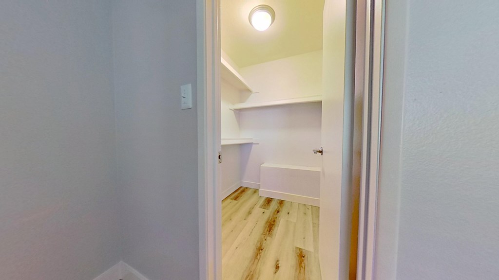 A white doorway opens to a small room with a bed and a light on the ceiling.