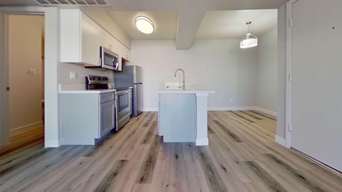 A kitchen with a white fridge and wooden floors.