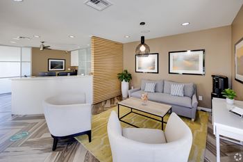A modern living room with a white chair, a grey couch, and a yellow rug. at The Viridian Apartments, Scottsdale, AZ