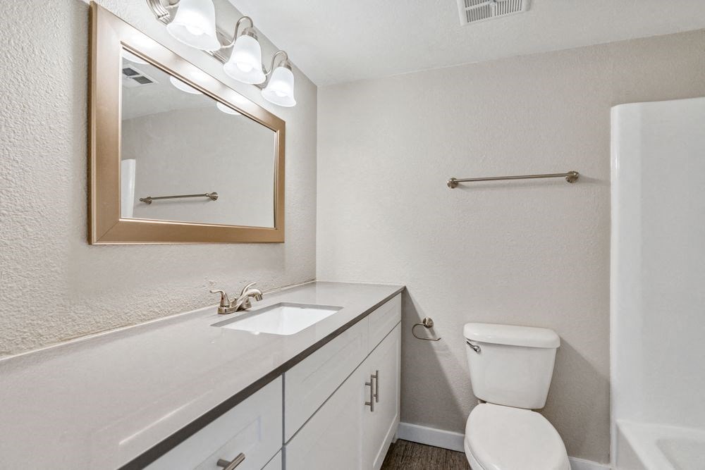 A bathroom with a white toilet, sink, and mirror at Tides on East Cactus Apartments, Phoenix, AZ