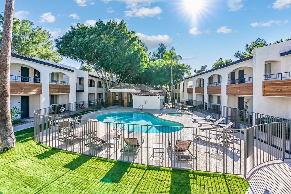 A sunny day at a resort with a pool and lounge chairs at Tides on East Cactus Apartments, Arizona, 85032