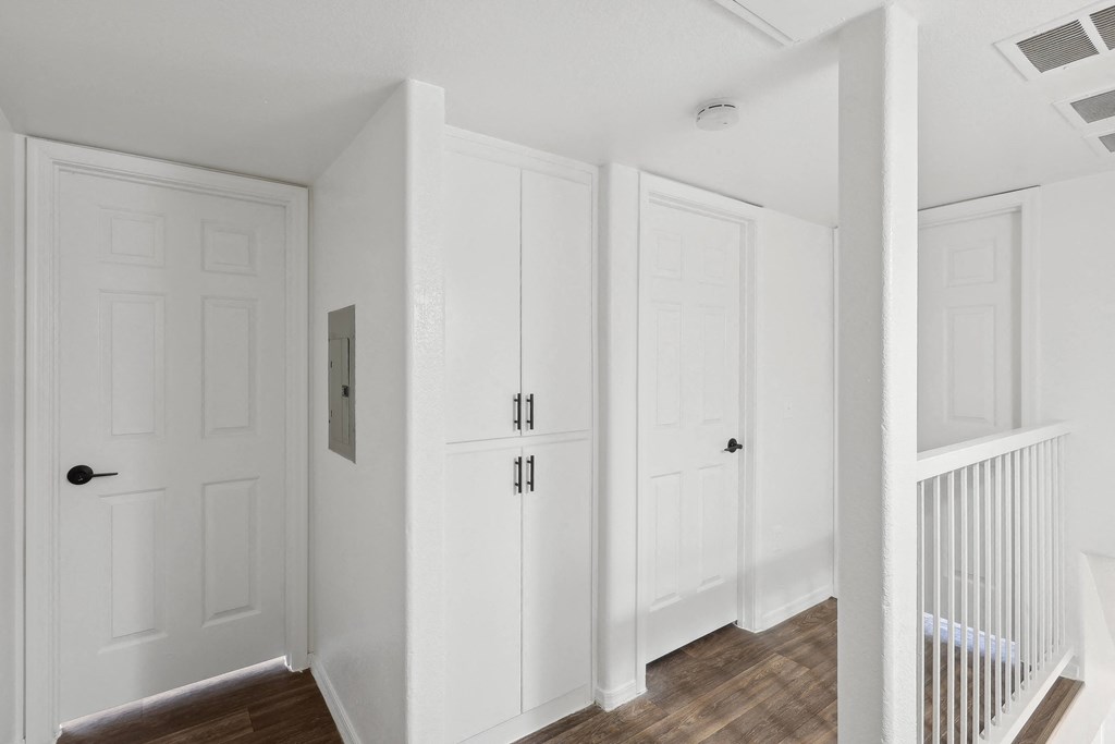 the hallway of a home with white doors and a staircase