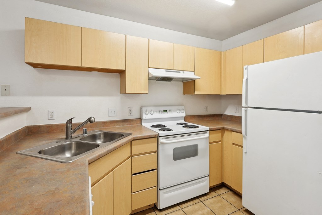 a kitchen with white appliances and wooden cabinets and a sink