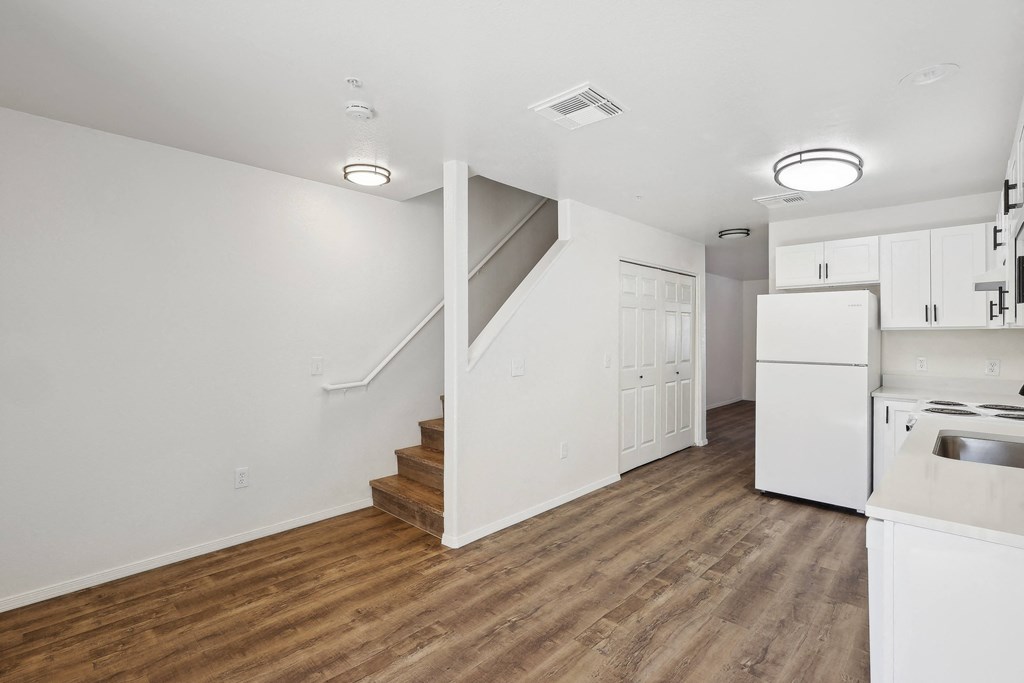 a renovated kitchen with white cabinets and white appliances and a white staircase
