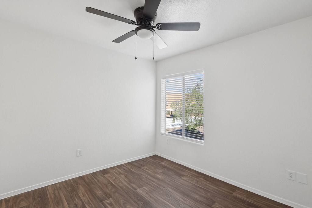 an empty room with a window and a ceiling fan