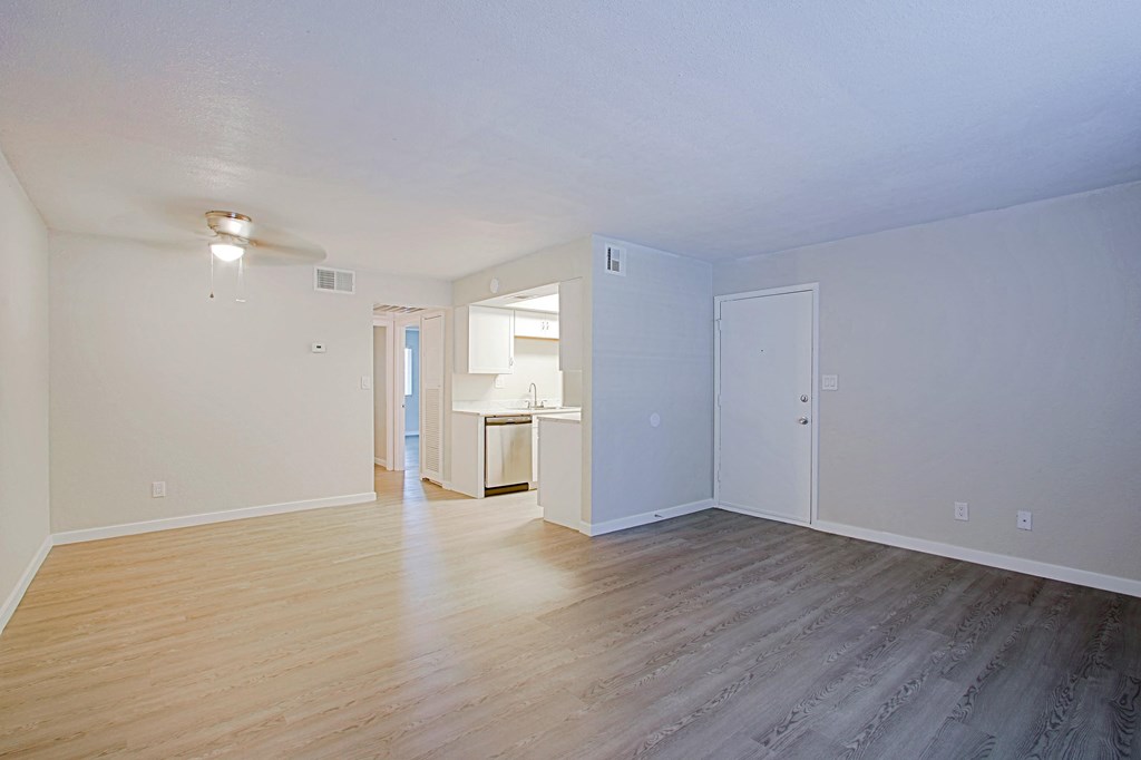 an empty living room with wood floors and white walls