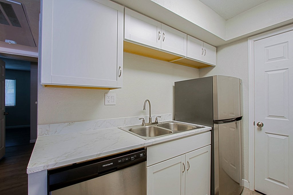 a kitchen with white cabinets and a sink and a refrigerator