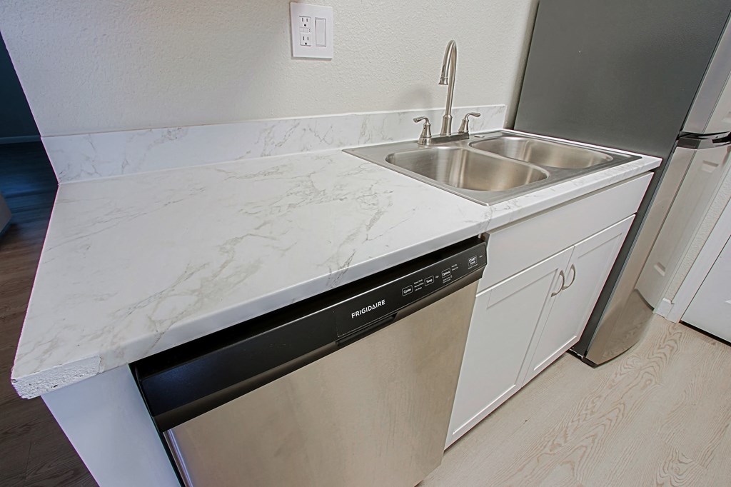 a kitchen with white marble counter top and a dishwasher
