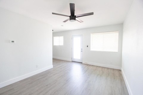an empty living room with white walls and a ceiling fan